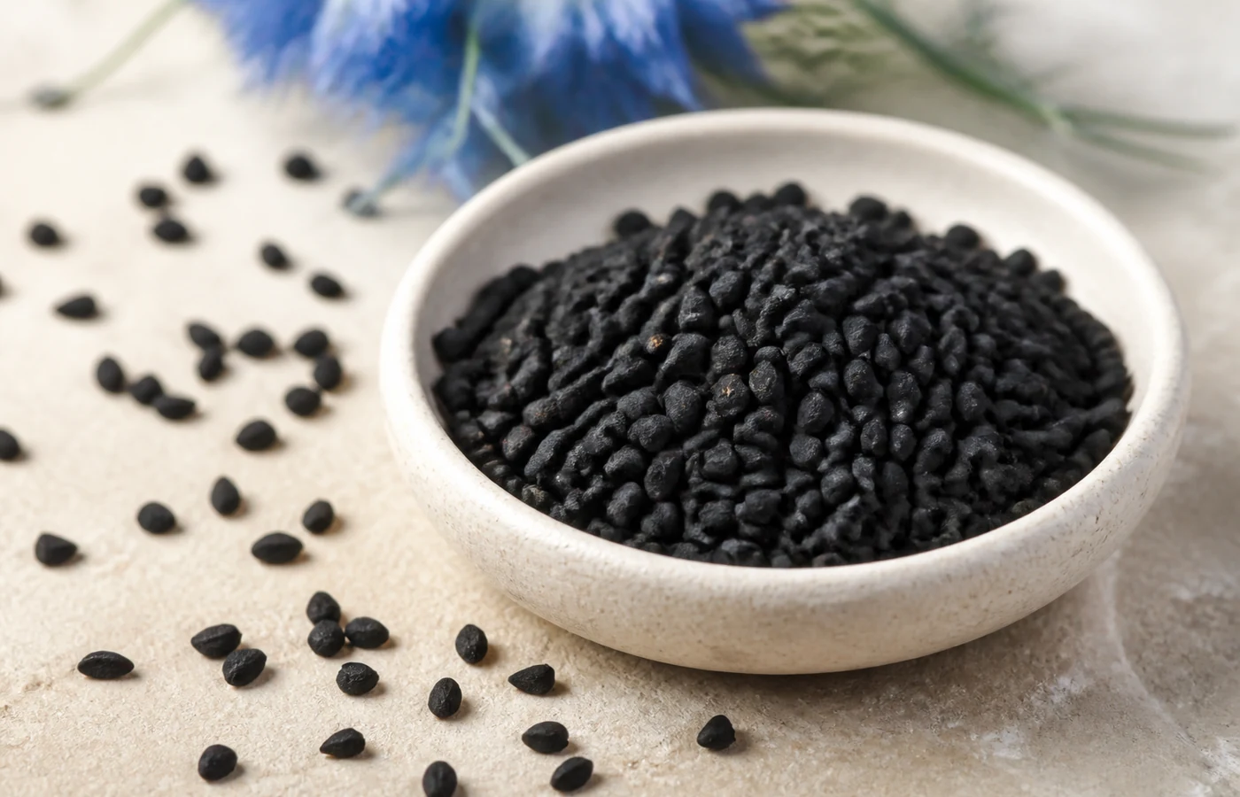 Petites graines noires et irrégulières de Nigella sativa dans une coupelle
